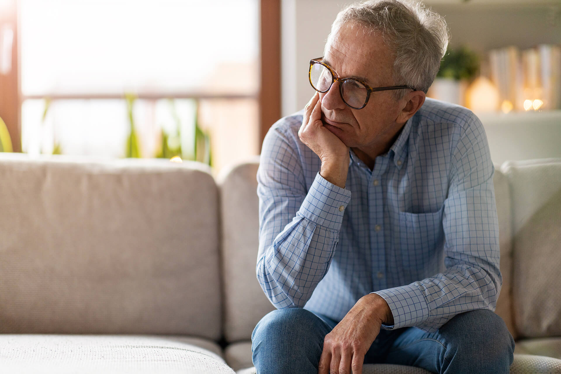 older man sitting on couch in a depressive state