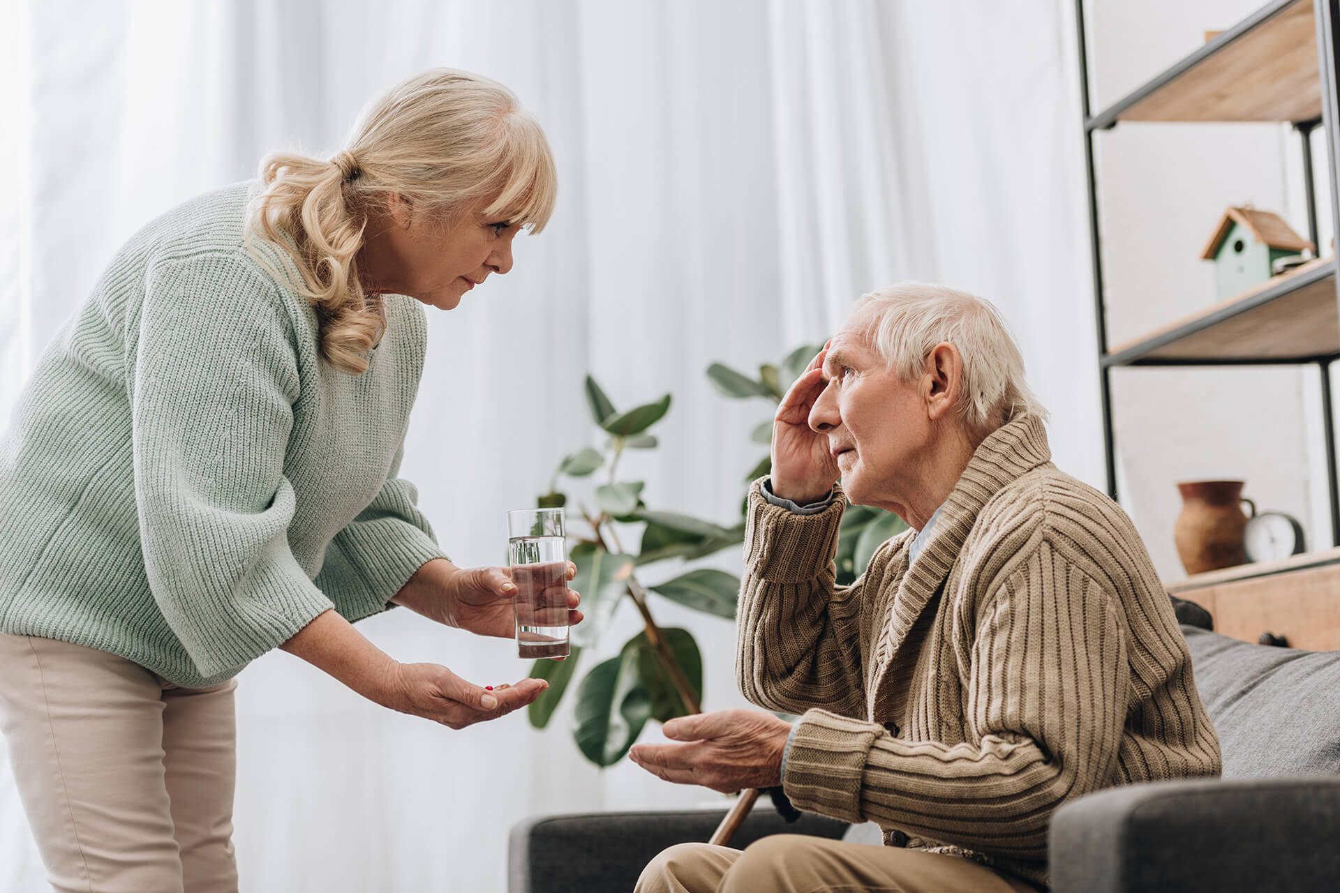 forgetful old man being helped by woman to take his medication